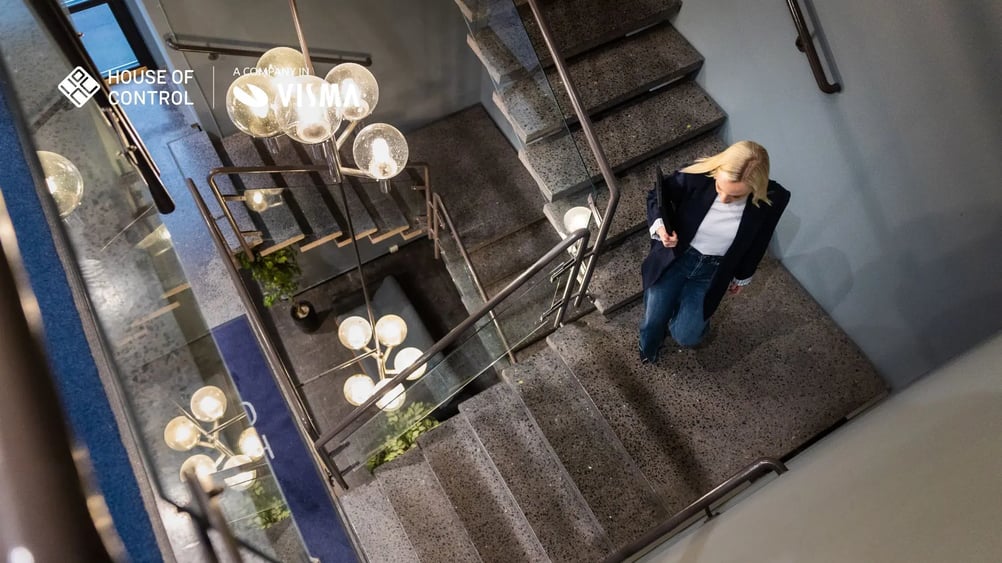 A blonde woman walking down the stairs at the office, wearing jeans and a blazer