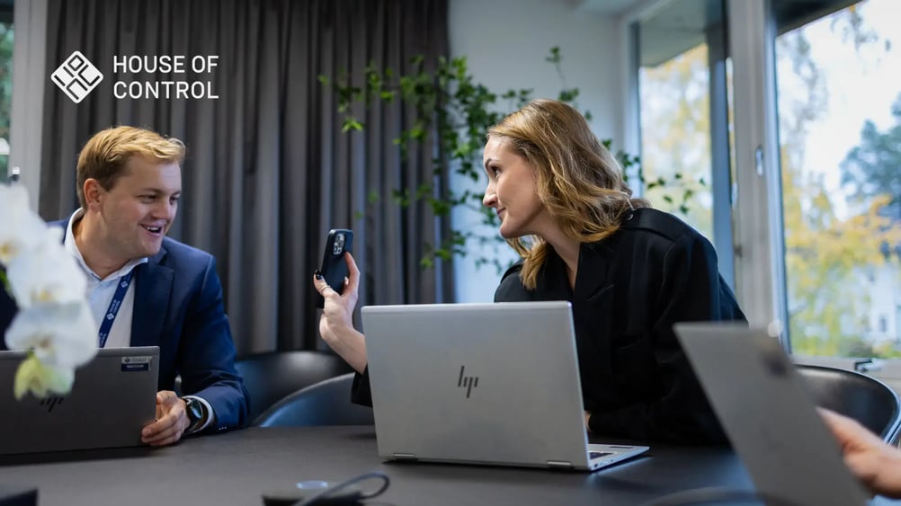 An employee at House of Control sitting down and showing her phone to her colleague
