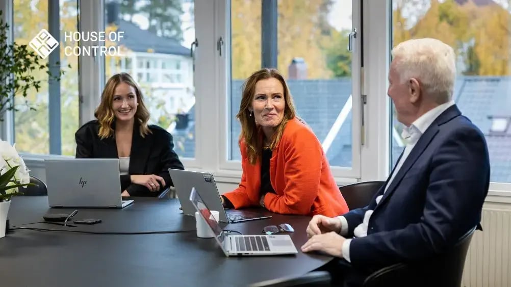 Three professionals having a discussion about IFRS 16 in a bright meeting room at House of Control. Two women and one man are seated around a table with laptops, smiling and engaged in conversation.
