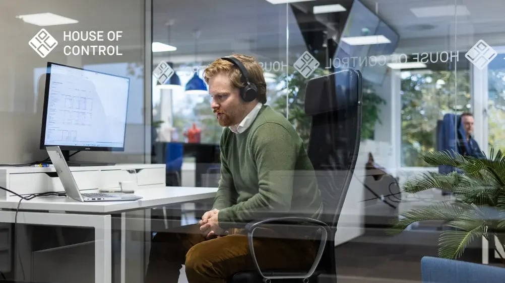 A house of control employee with headset in front of computer