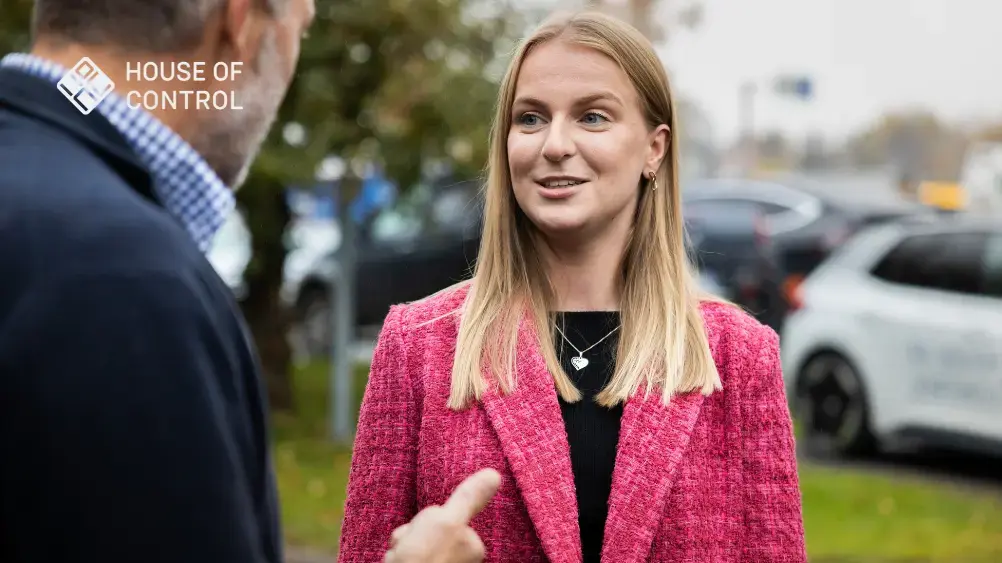 Dame i rosa blazer som står i en samtale
