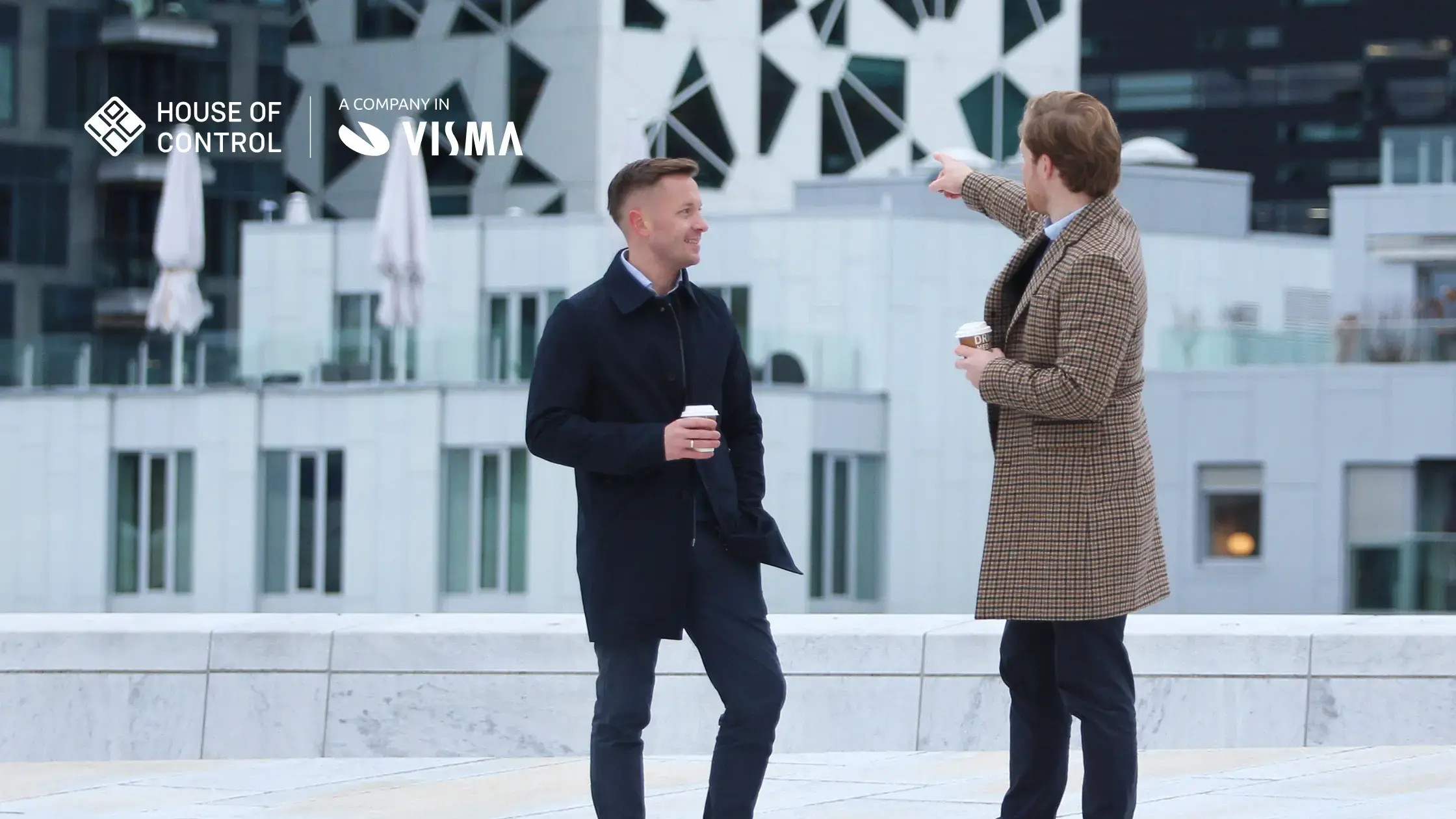 Two men in the city, one is pointing at the buildings in the background