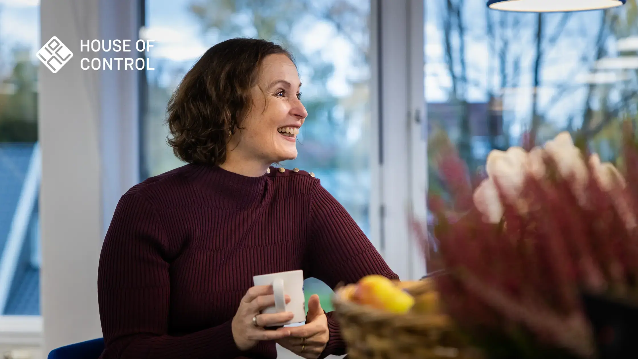Dame smiler med en kaffekopp i hånden