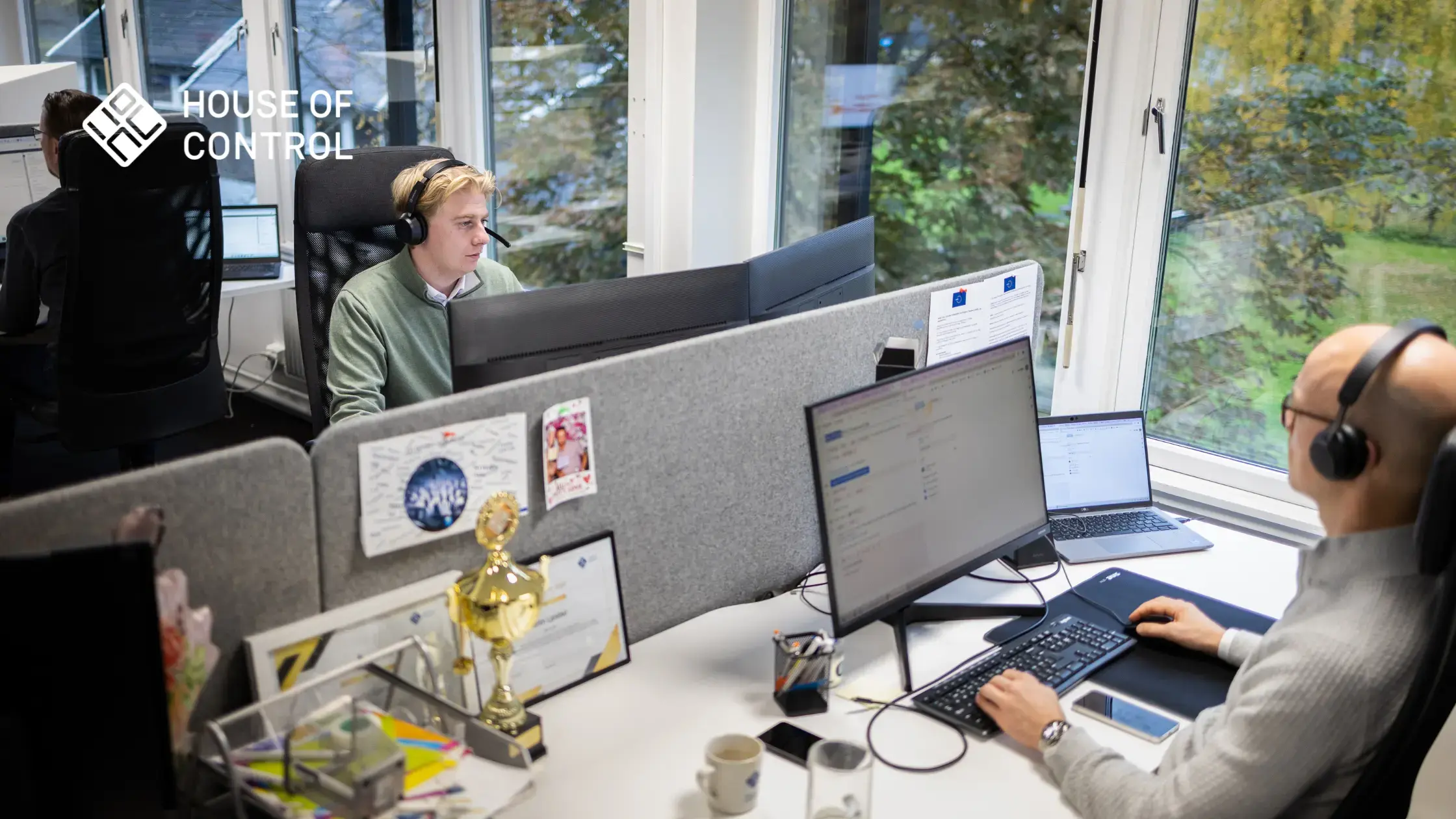 Tre menn som sitter foran PC-er