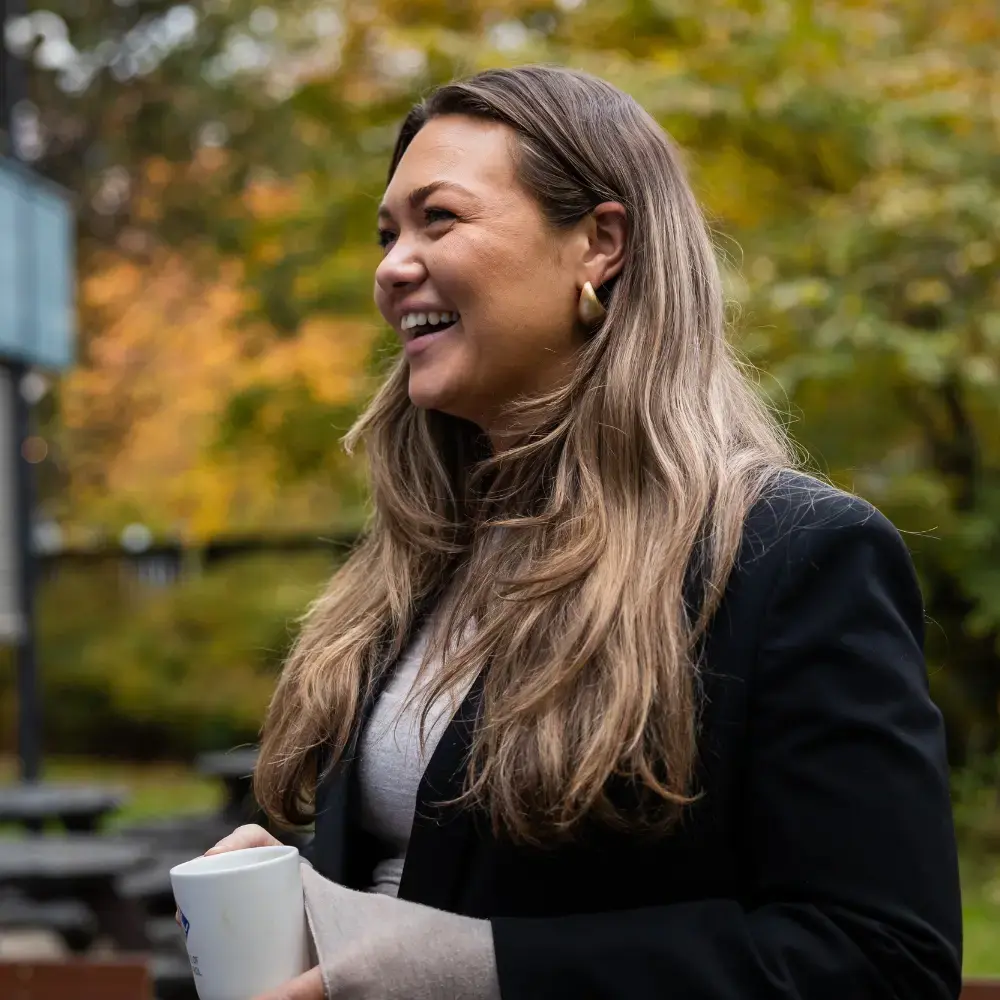 A brown haired woman is outside smiling