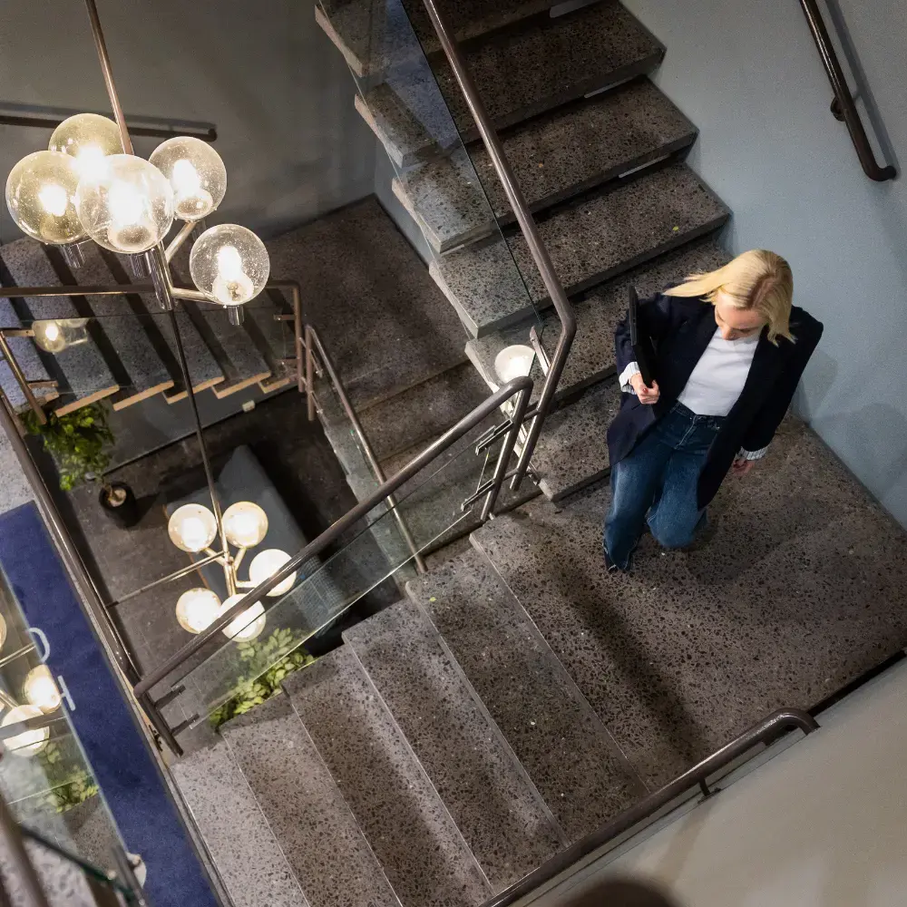 A blonde woman is walking down the stairs at the office
