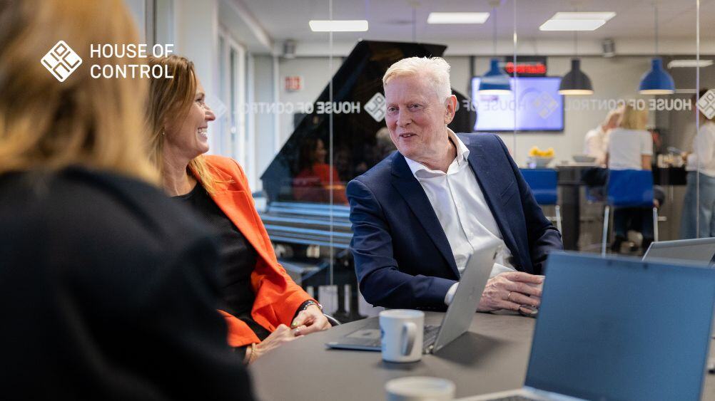 Colleagues having a business discussion in a modern office at House of Control, with laptops and coffee cups on the table.