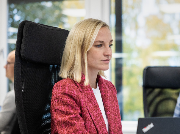 Kvinne-i-rosa-jakke-og-blondt-hår-kigger-på-skjermen